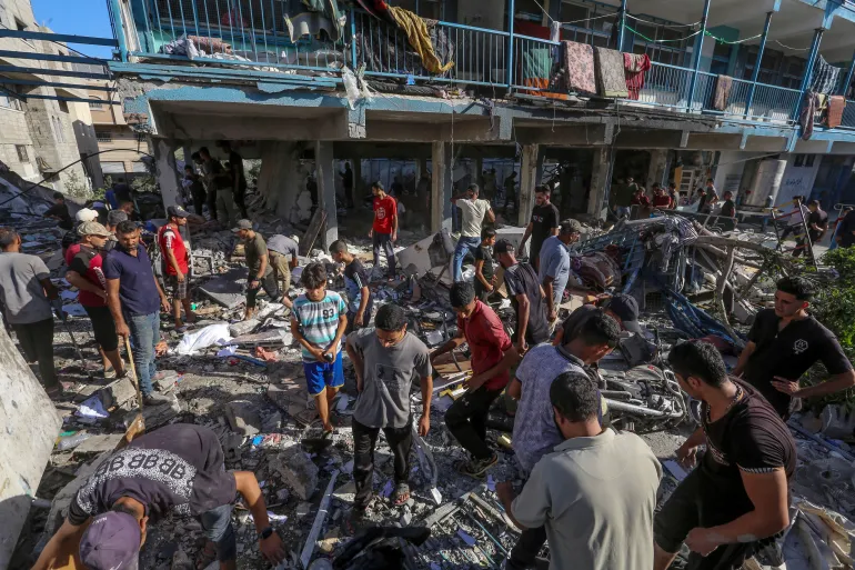 Palestinians search for missing people under the rubble of the destroyed UNRWA-run al-Jaouni school following an Israeli air strike in the Nuseirat refugee camp, central Gaza, September 11, 2024