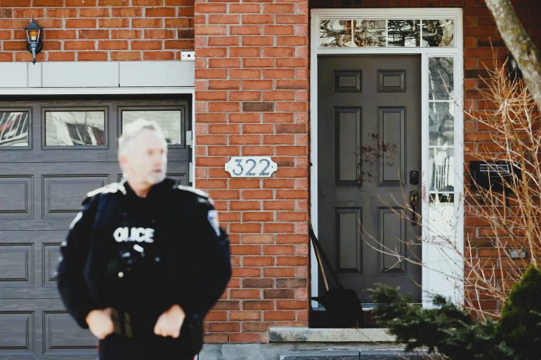 photo: An Ottawa Police Service officer stands near a door smeared in blood in Ottawa suburb of Barrhaven