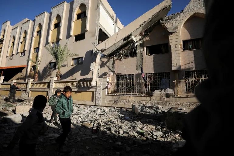 Palestinian children walk at the site of an Israeli strike on a school sheltering displaced people in Gaza City.