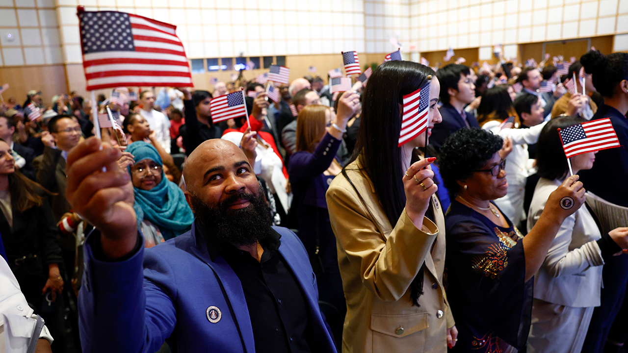 About 200 people wave American flags after being sworn in at a naturalization ceremony in Boston on April 17, 2024. 